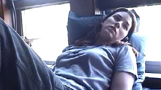 Pandora reclining on a bus, a window behind her.