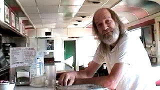 David, an older man with a white beard, at a diner counter.