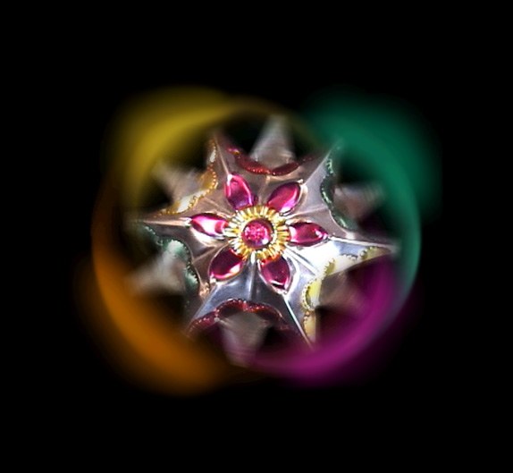 El emblema de Poesía Densa: una estrella-flor enjoyada que brilla sobre negro con estelas de luz de colores.
